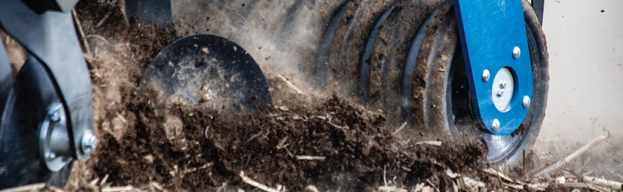 Mach Till tillage implement detail - close up of discs ripping soil with dirt