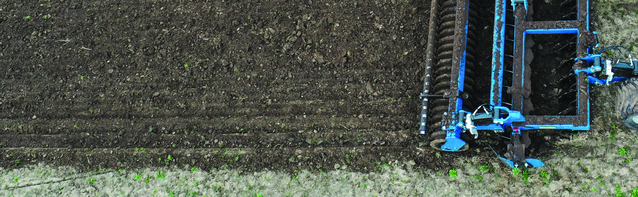 Mach Till tillage implement detail - close up aerial view of Mach Till actively tilling, with untilled soil next to and in front of the unit